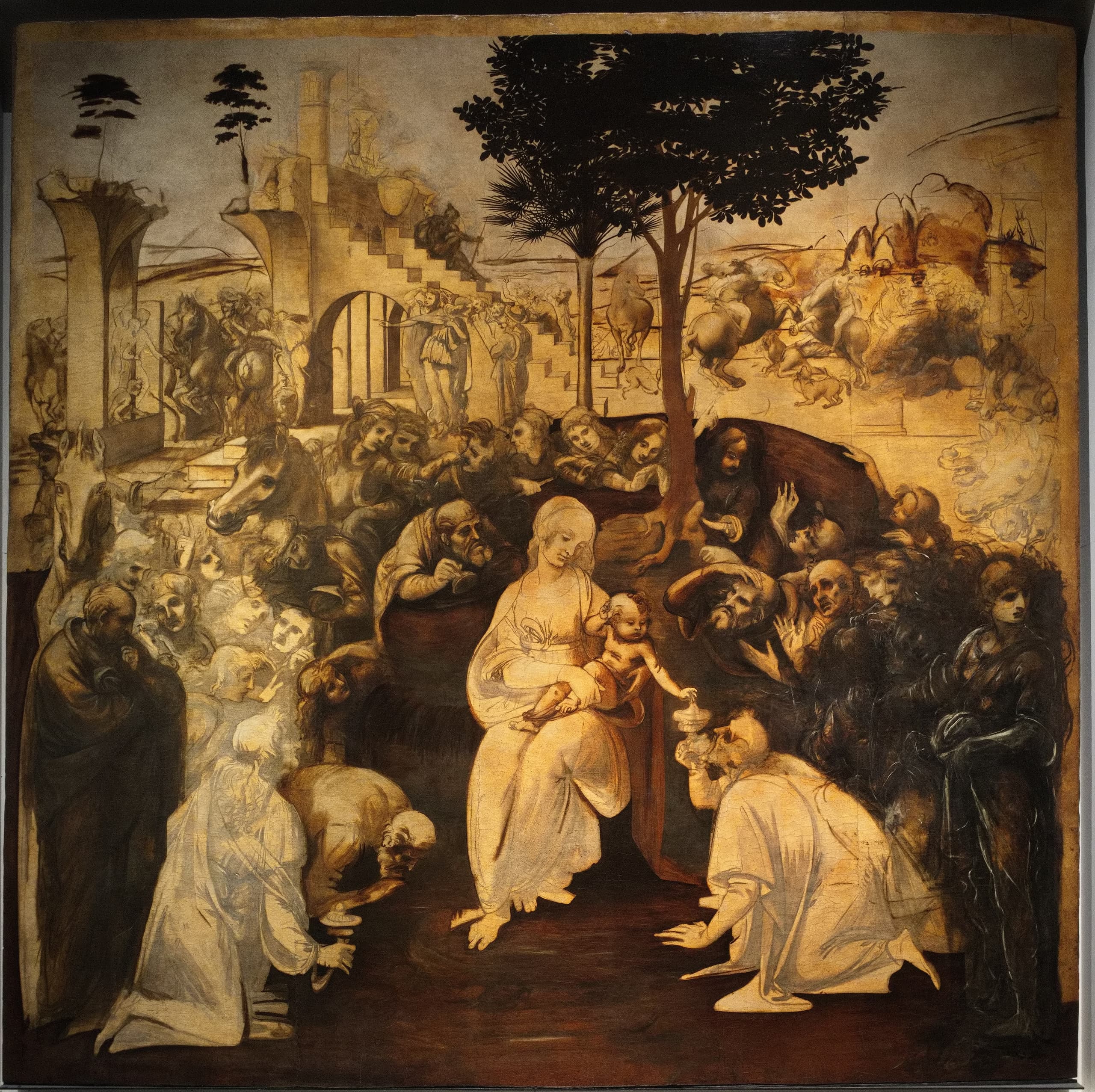 Large nearly square panel in brownish monochrome: a seated woman with a child at the centre, surrounded by crowded kneeling and standing figures, with lighter architectural forms and open space above.
