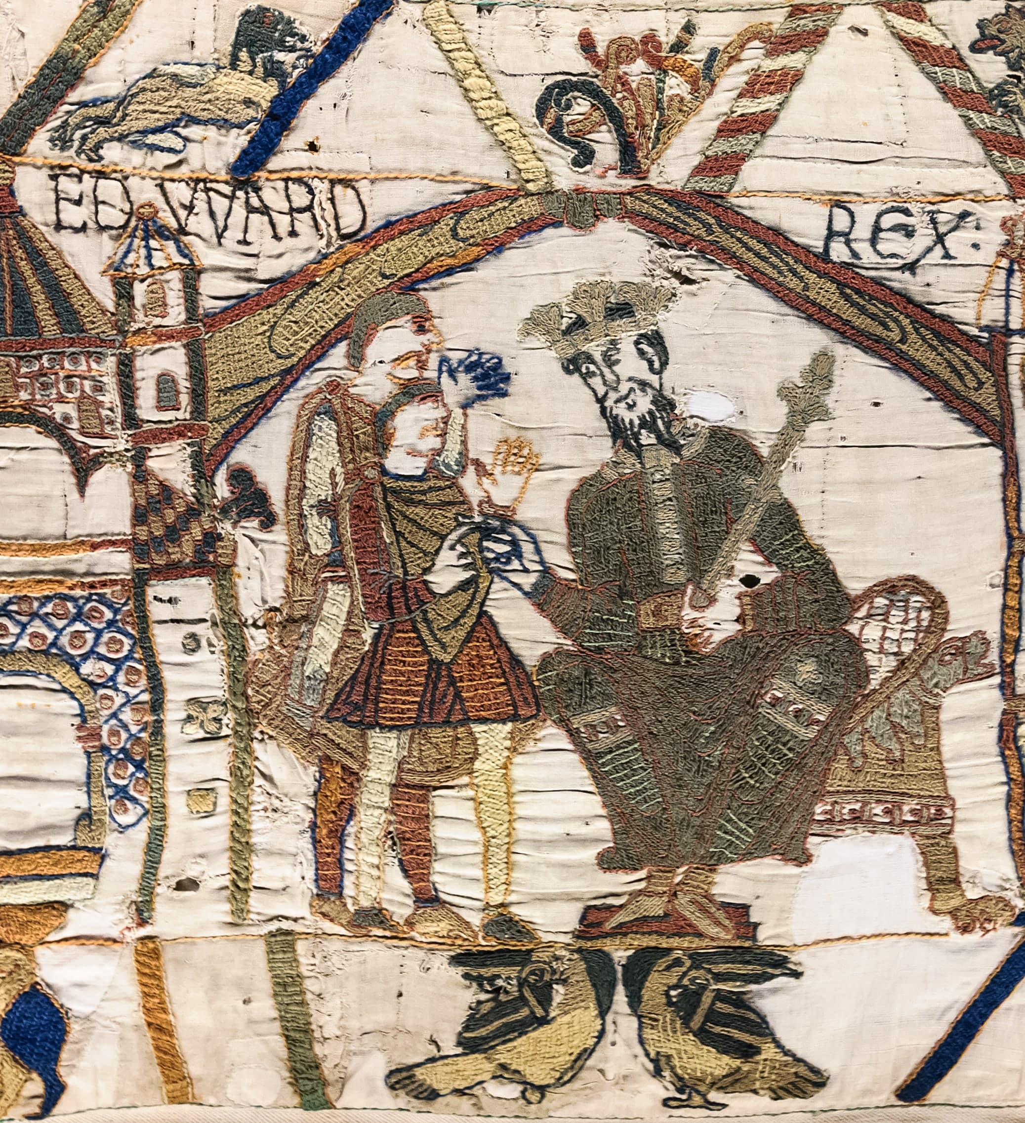 A long horizontal strip of embroidered linen showing armed figures, horses, ships, and a building, with borders above and below carrying animals and smaller figures.