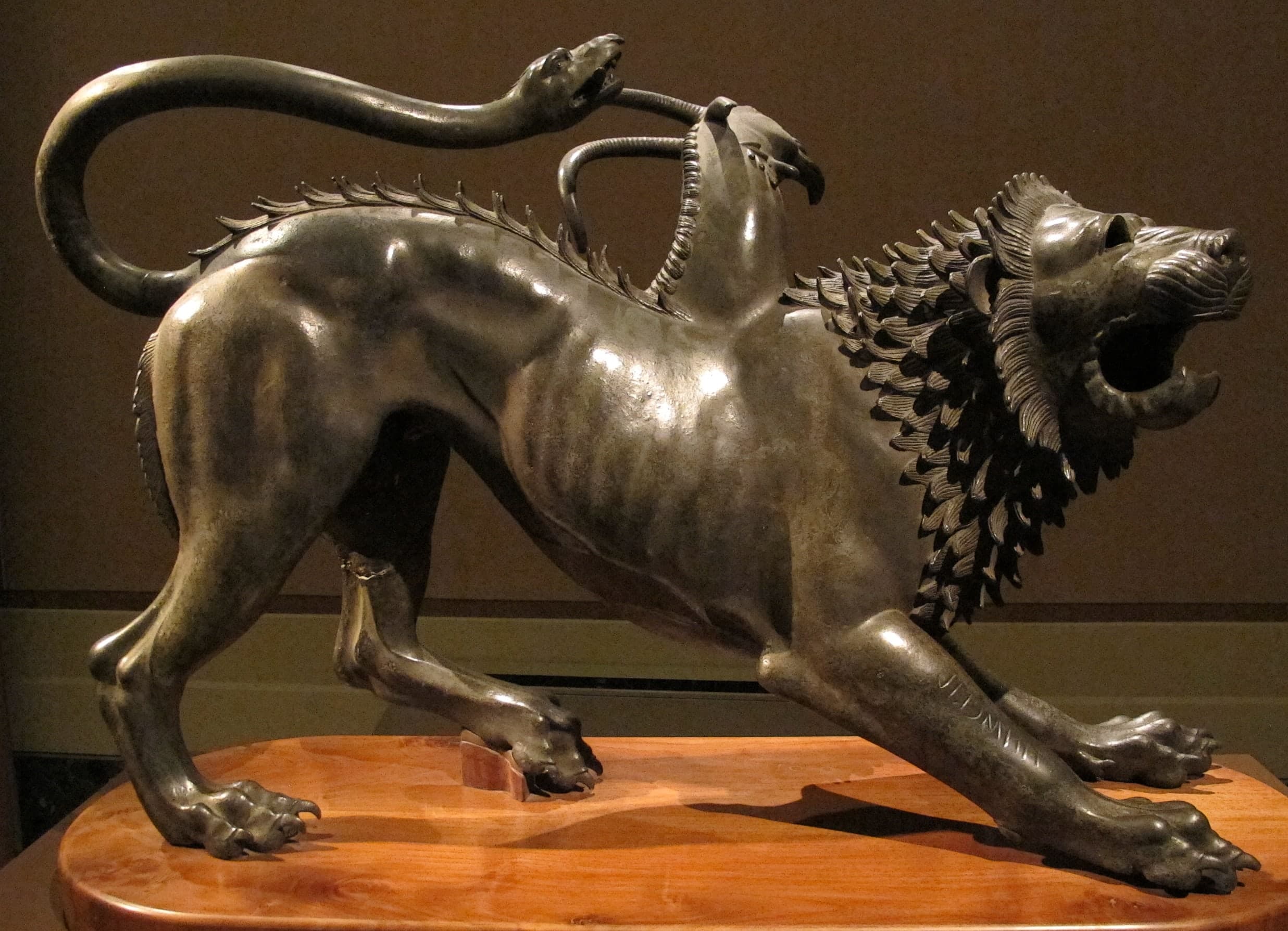 A bronze beast with a lion’s snarling head and body, a goat’s head rising from the back, and a serpent for a tail, fixed in a taut, combative stance.