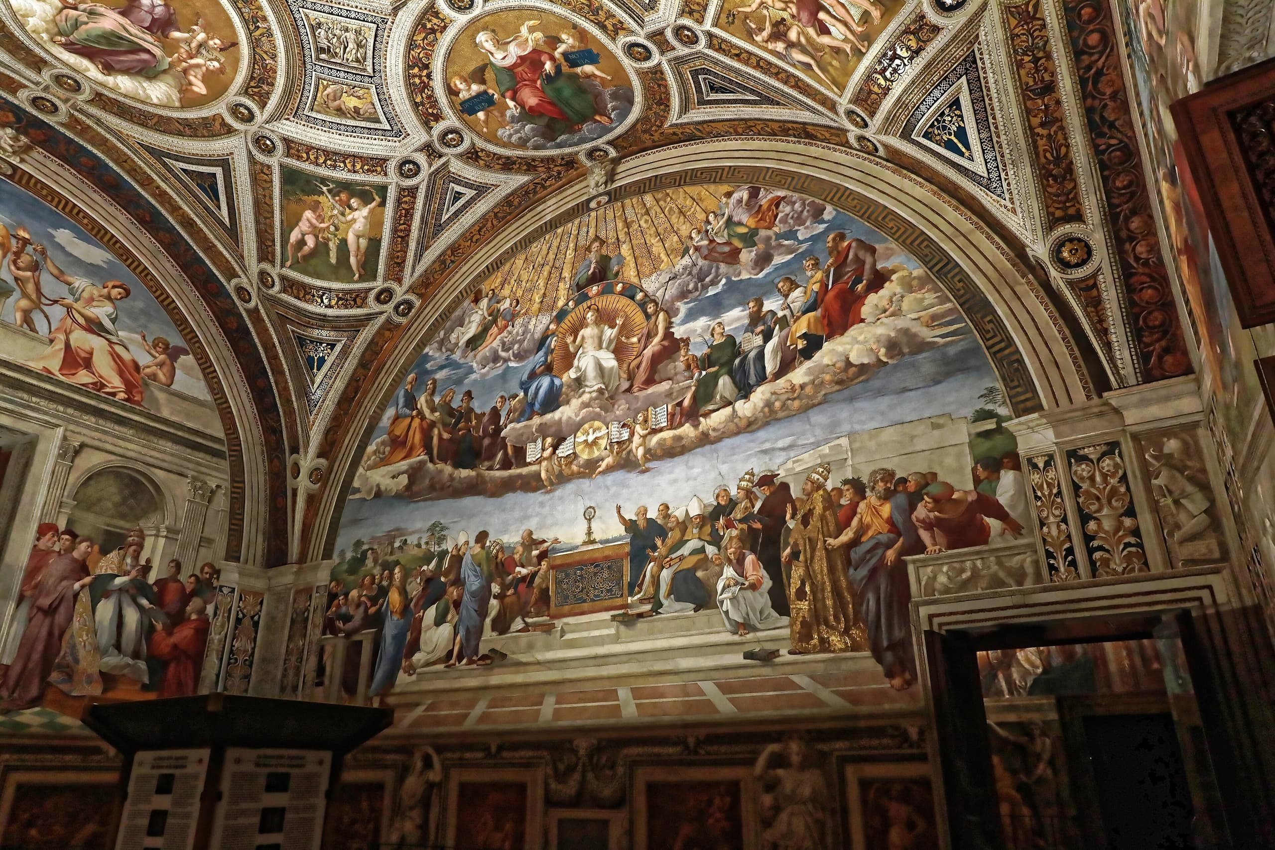 A wide fresco split into two zones: a golden upper register of holy figures in a curve of light, and a lower crowded terrace of people gathered around an altar bearing the sacrament.