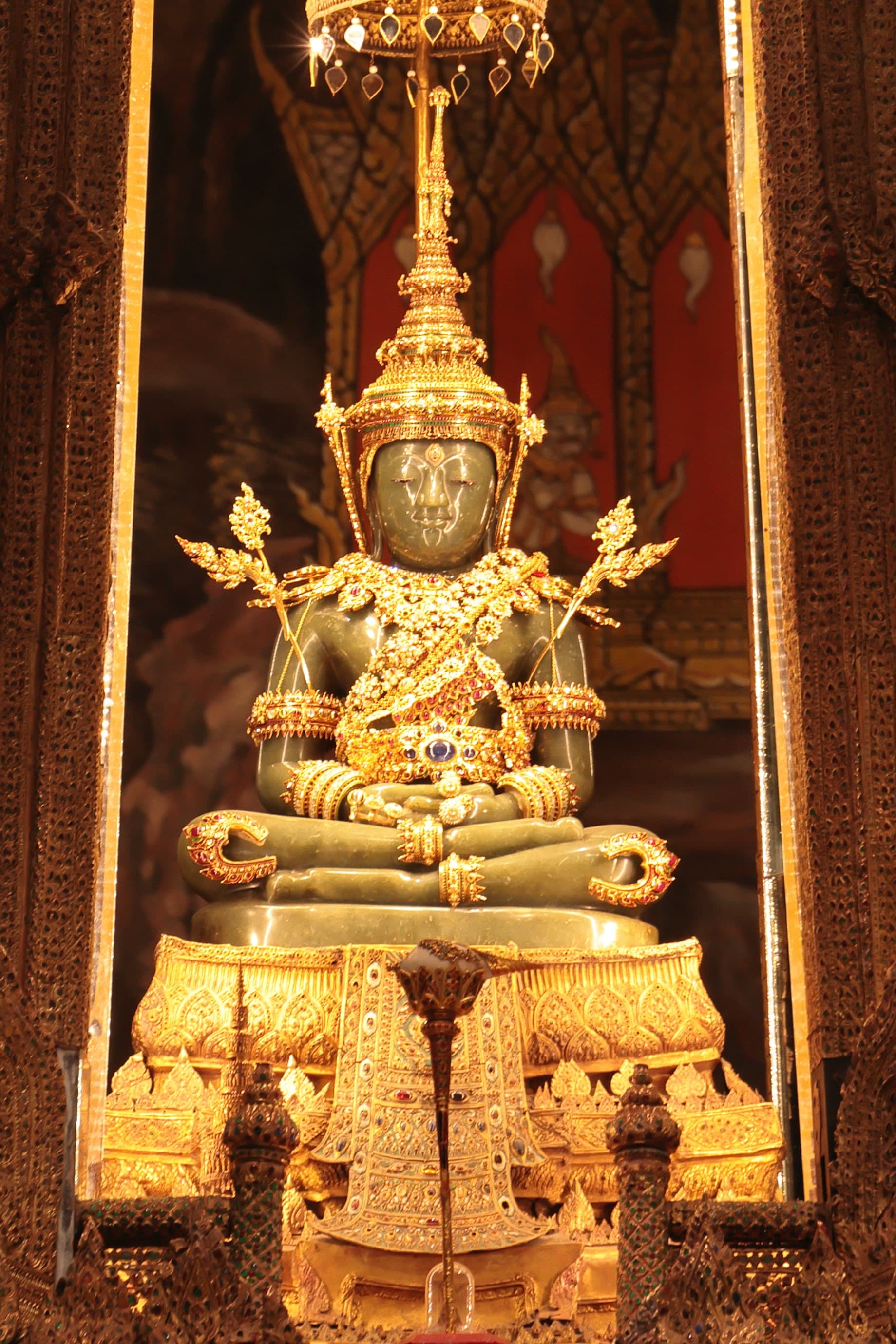 A small seated Buddha in green stone, legs folded, hands in a meditative gesture, the figure compact and smooth under even light.