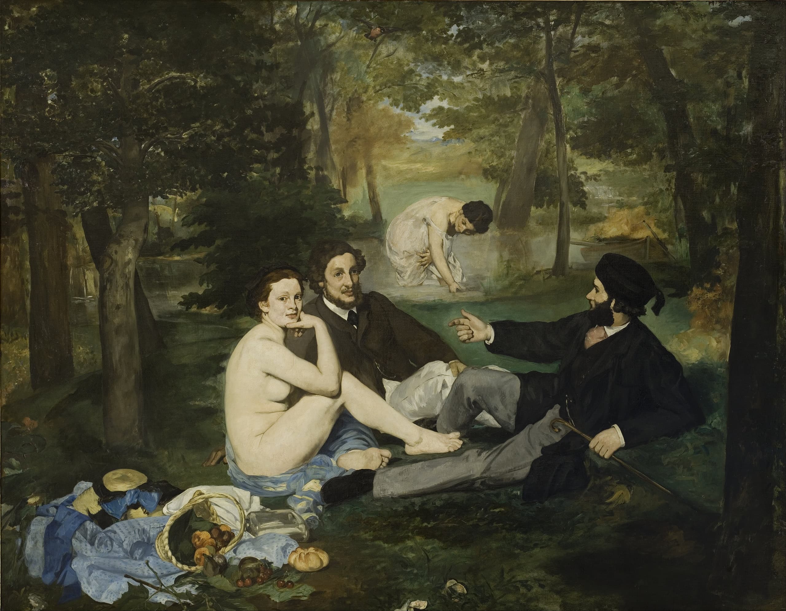 In a wooded clearing a nude woman sits on the grass beside two fully dressed men; a fourth woman bathes in the distance. A basket of fruit and discarded clothes lie in the foreground.