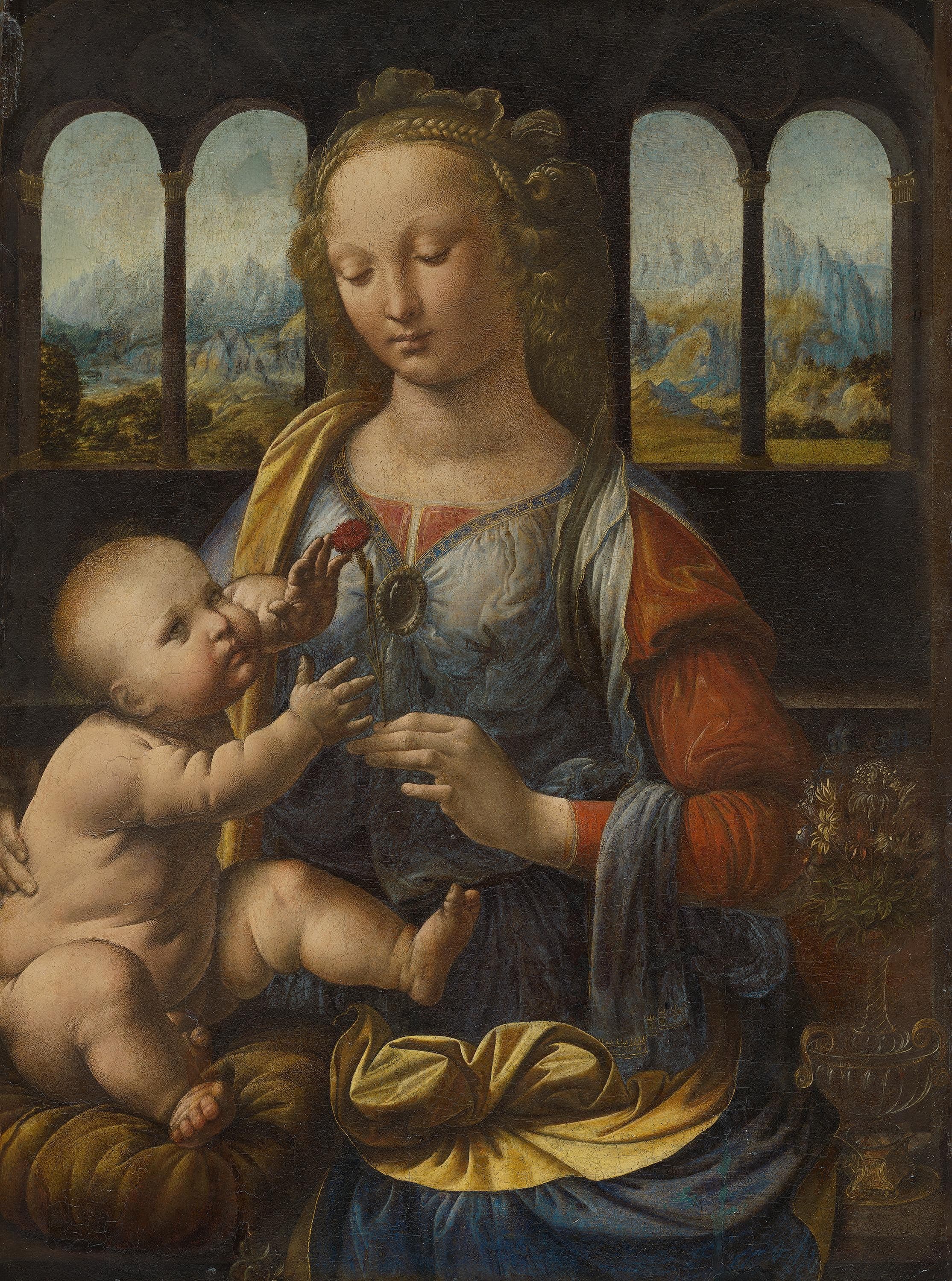 A young woman in rich dress sits holding a naked infant on her lap in a dim room with windows to either side; her left hand offers a small red flower held partly in shadow while both faces catch the light.