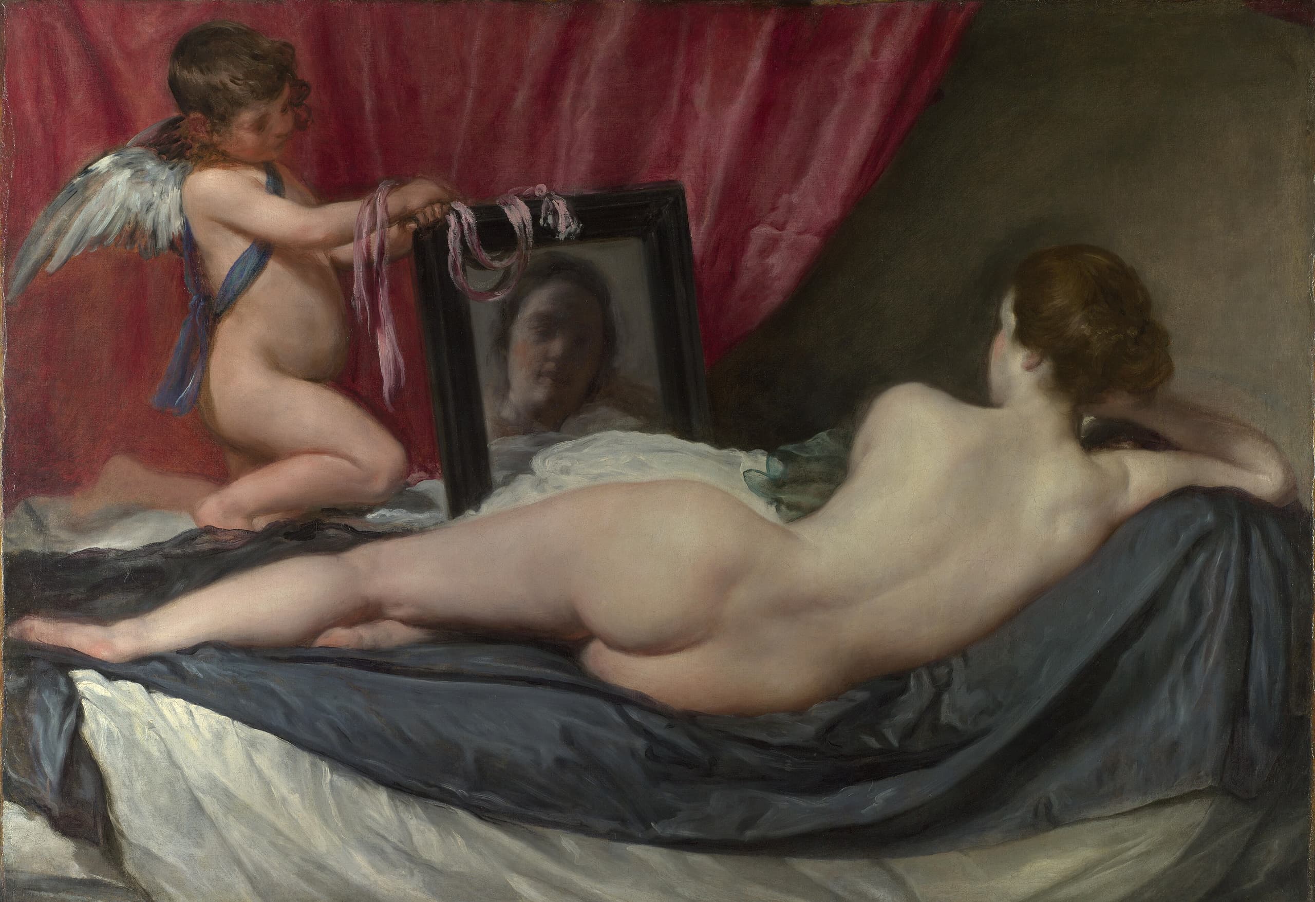 A woman reclines across a wide canvas with her back to the viewer, lying on pale drapery. A winged boy holds up a dark-framed mirror in which a face appears, turned outward.