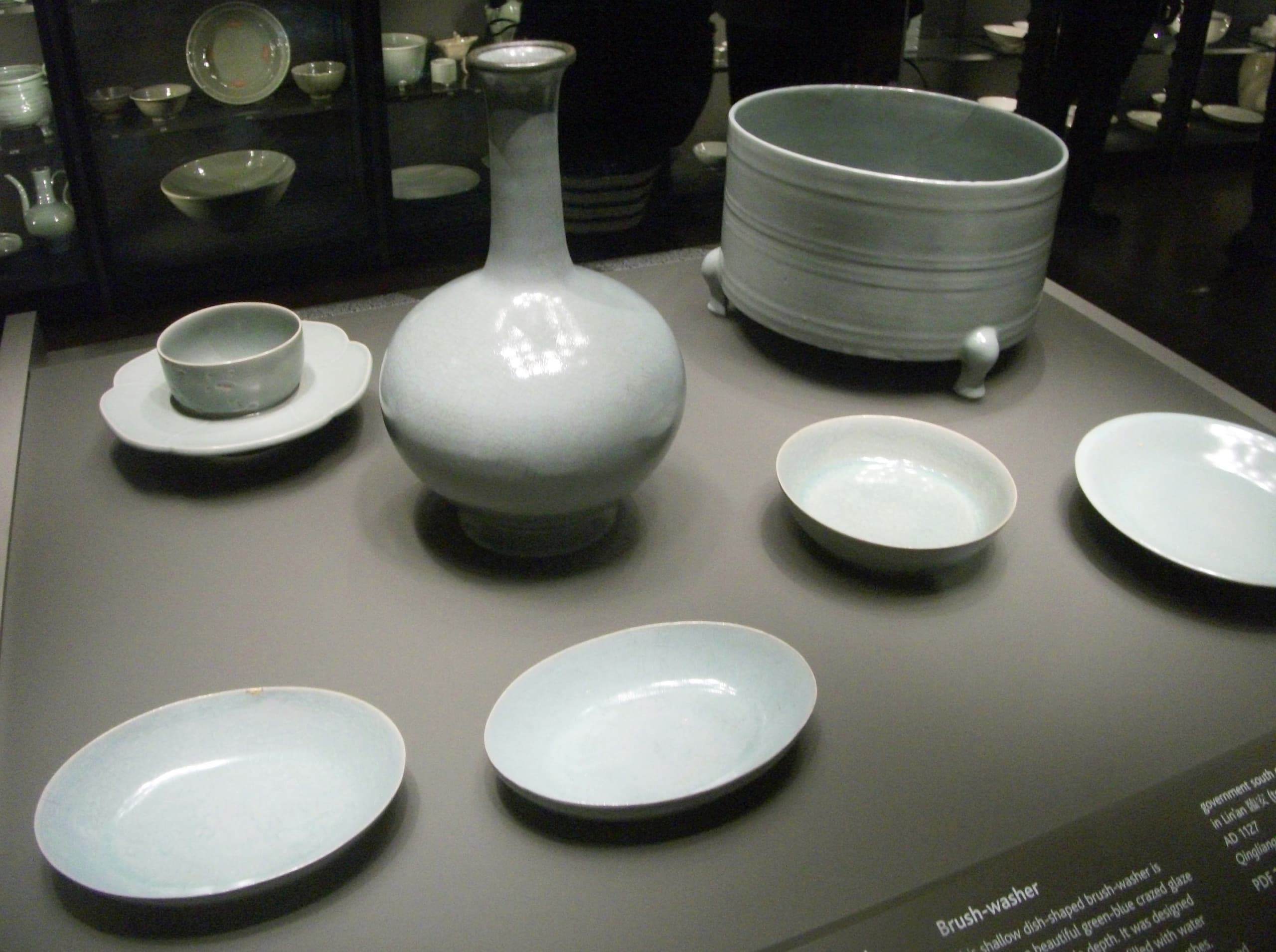 A shallow ceramic dish with gently curved sides, covered in a pale blue-grey glaze with a fine network of darker crackle lines across the surface.