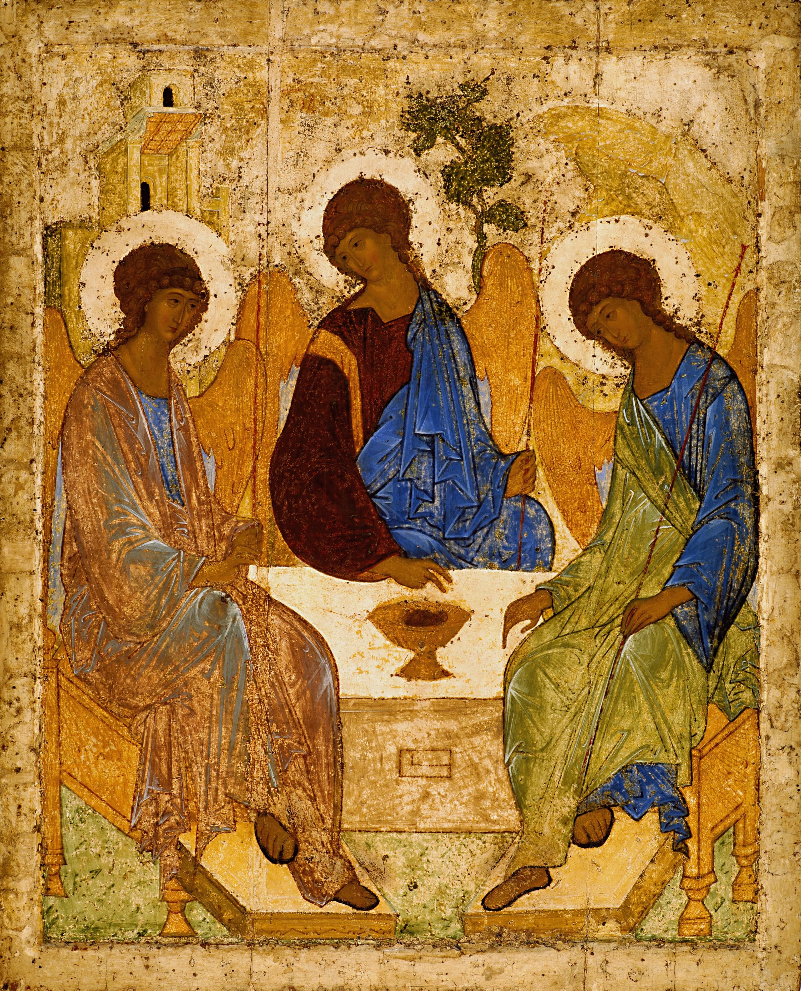 Three winged figures in robes seated around a small table, heads bowed toward a chalice at the centre, against a gold background.