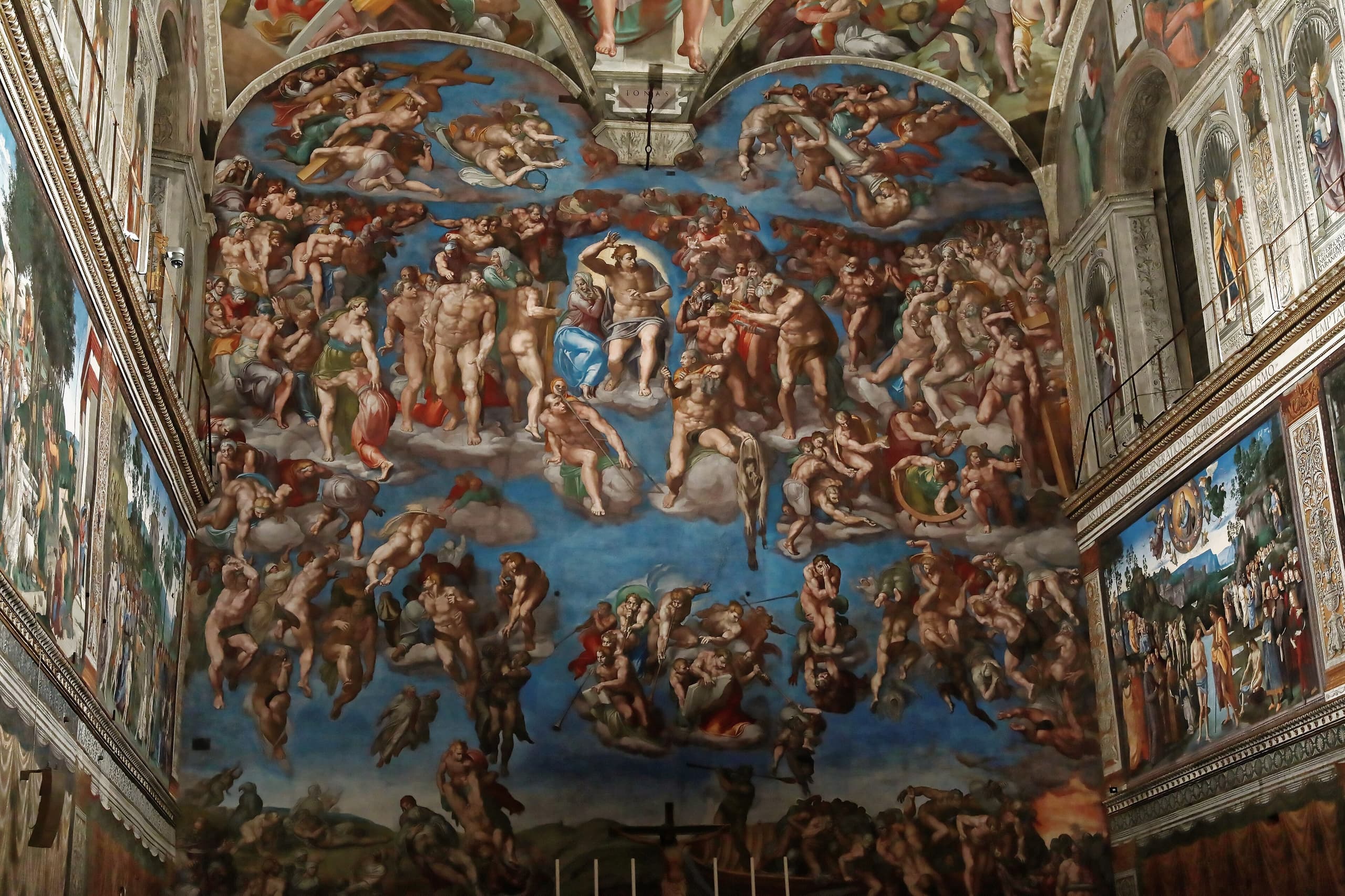 A vast crowded wall of figures around a central Christ: bodies rising on one side and falling on the other, saints packed above, flesh tones and sky dominating the field.