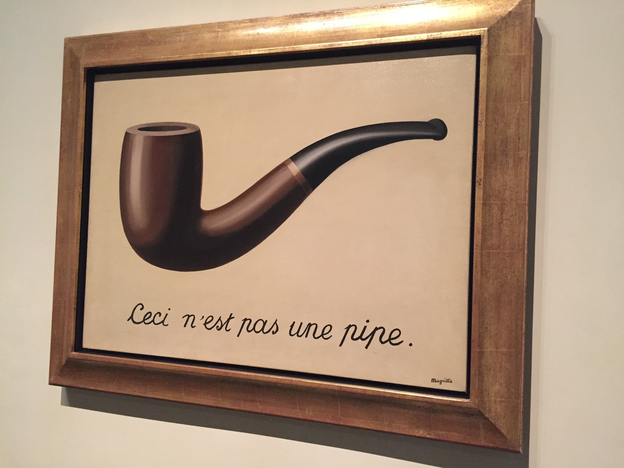 A wooden tobacco pipe floats alone against a pale, empty ground. Below it, in neat dark cursive, a French sentence runs in a single line across the lower part of the canvas.