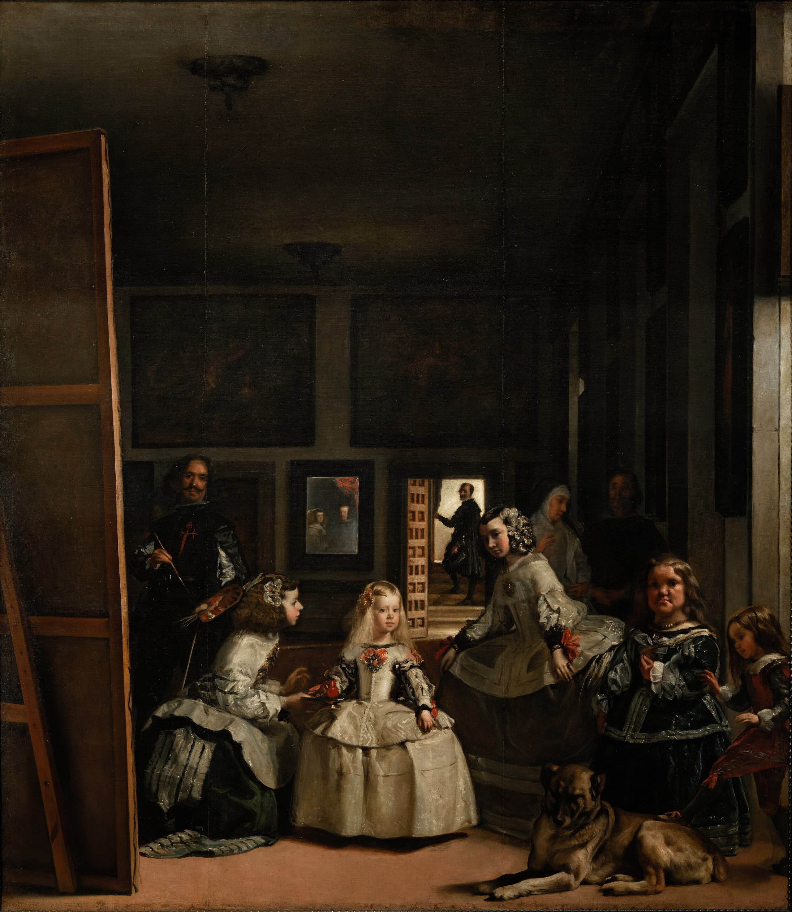 A dim, high-ceilinged room. A fair-haired child in a pale silver dress stands in a wedge of light, flanked by attendants and a large dog. At the left a man stands behind the reversed back of a very large canvas, brush raised. At the rear, a small bright rectangle holds two indistinct figures, and a man stands in a lit doorway.
