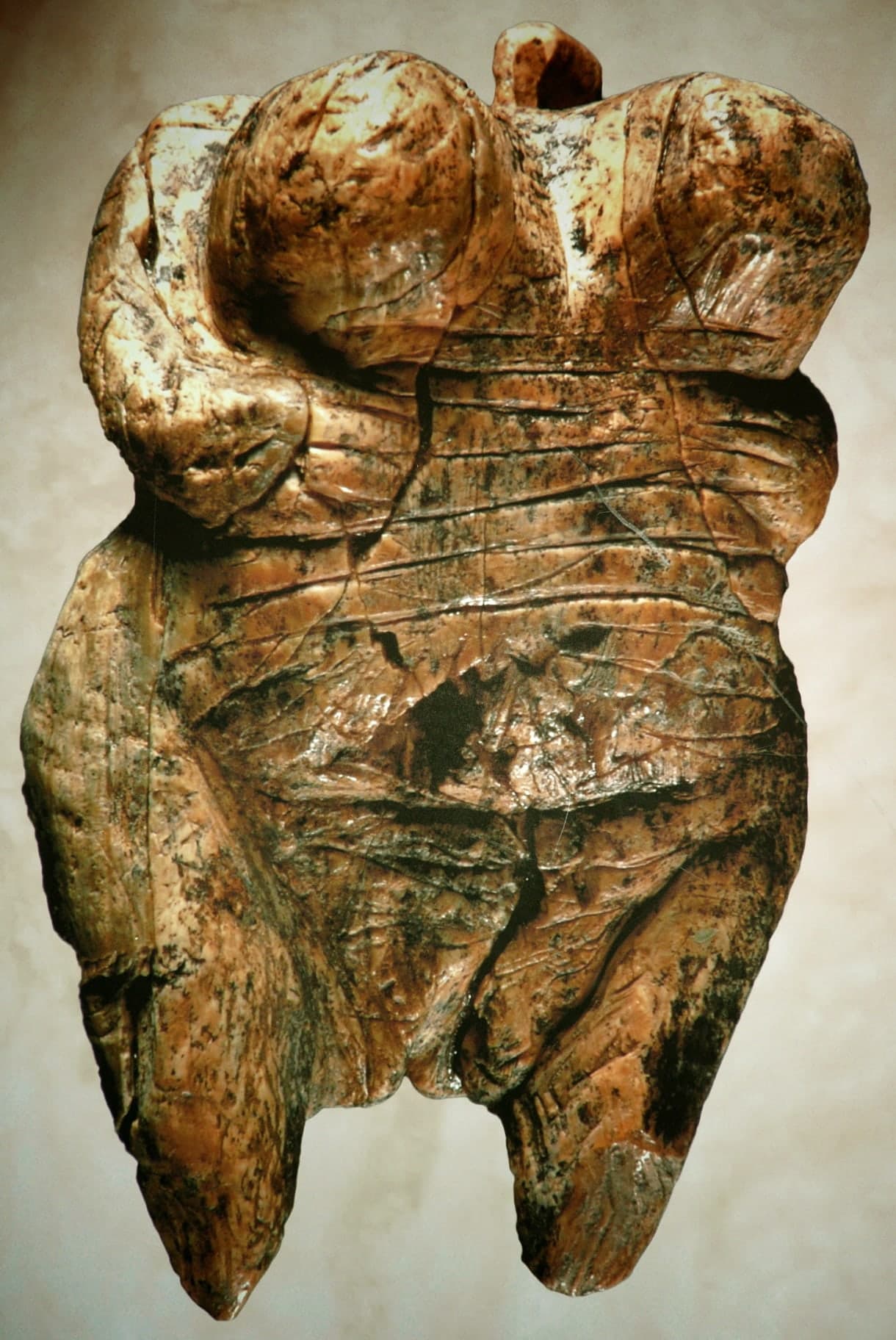 A small freestanding figurine carved in pale ivory, presenting a compact human body shaped for the hand rather than for a wall.