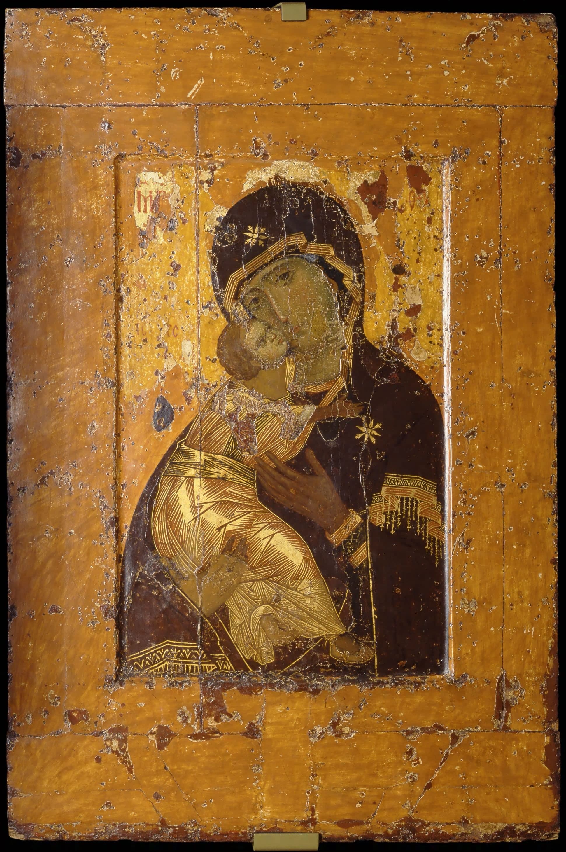 A vertical tempera icon: the Virgin holds the Child against her, their faces touching. Her eyes look outward; his body turns into her cheek. Dark drapery and worn gilding surround the two heads.