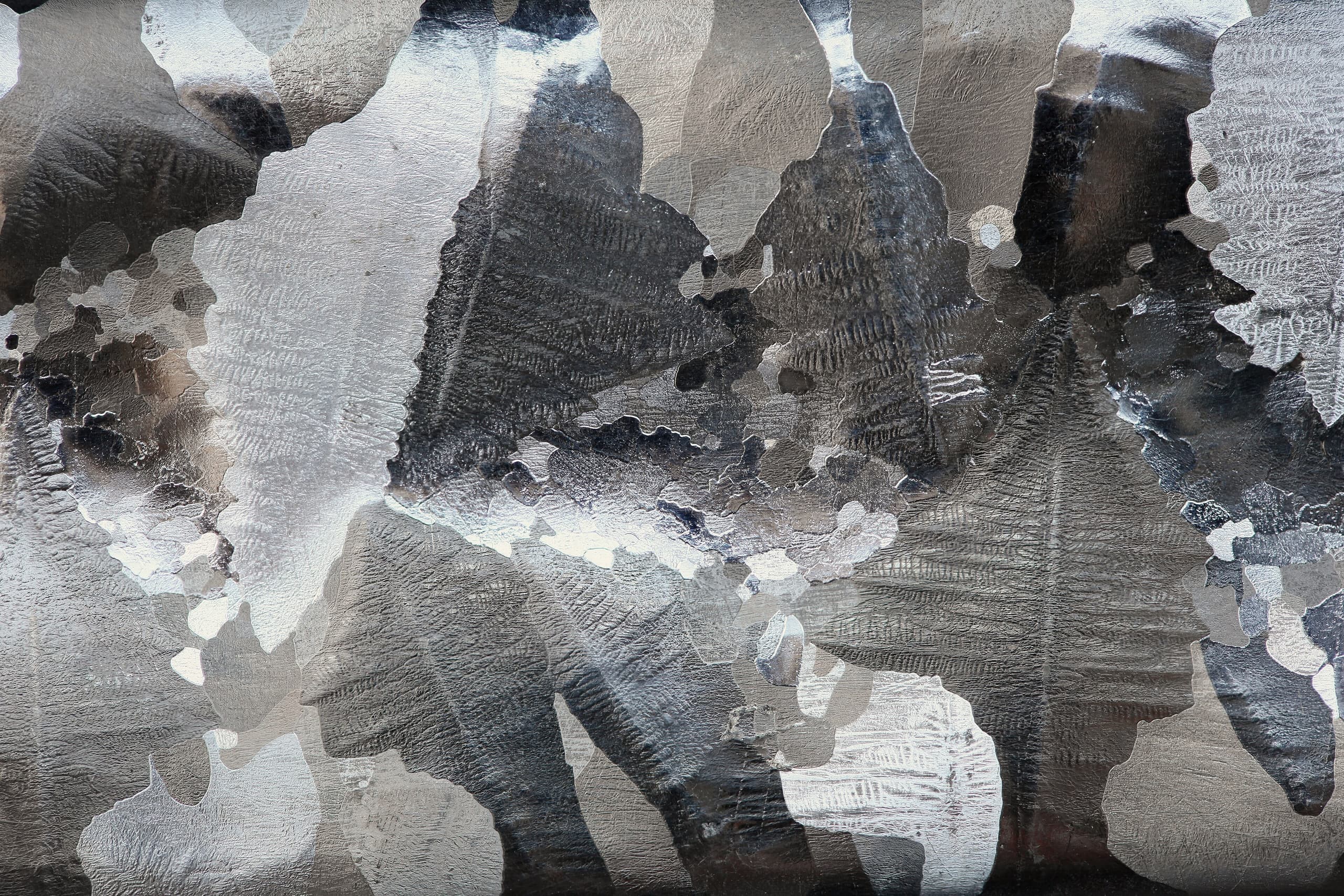 A sample of silvery-grey aluminium metal, showing its reflective surface and light metallic lustre.