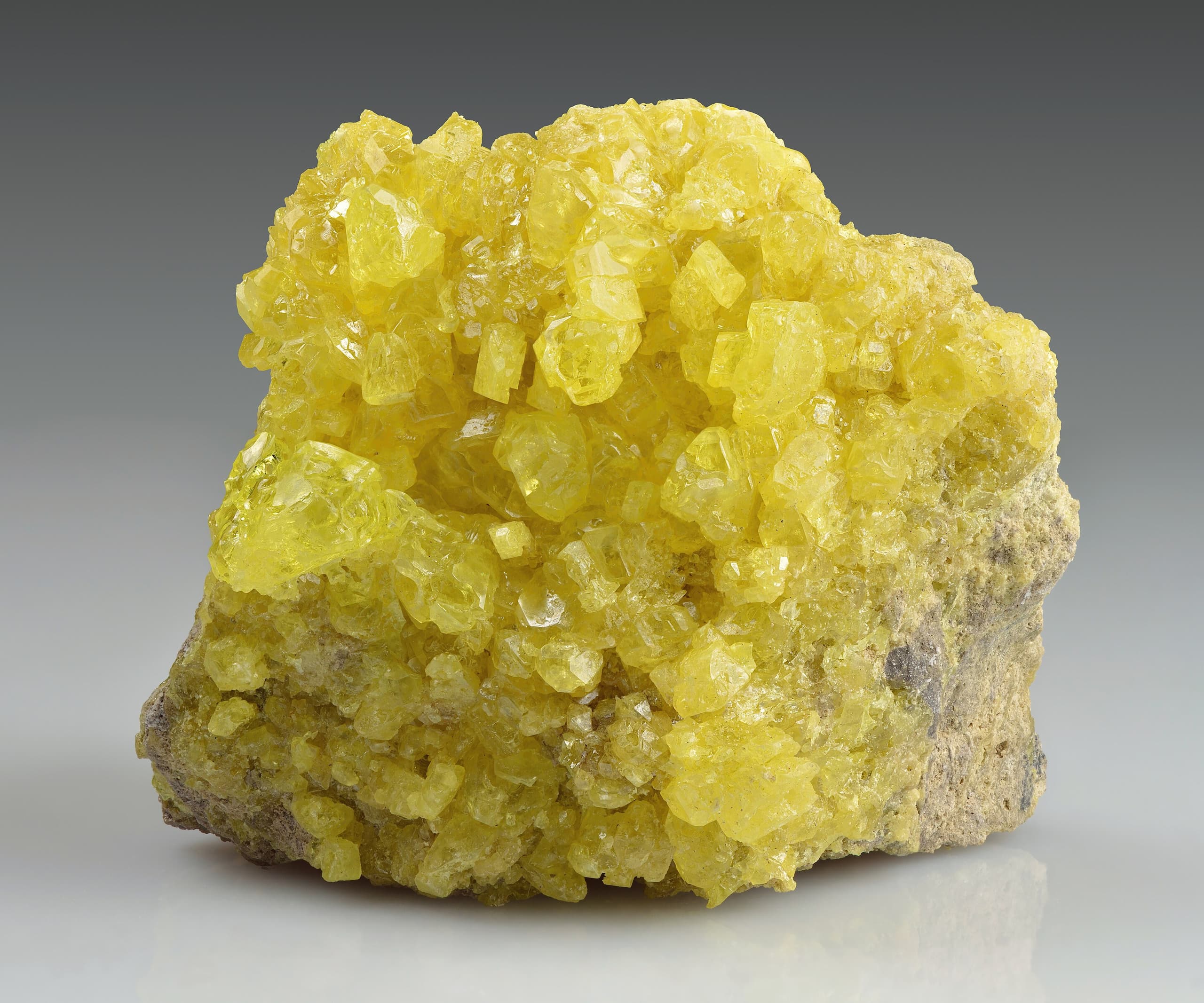 Bright yellow crystalline chunks of elemental sulfur, angular and translucent, clustered together against a plain background.