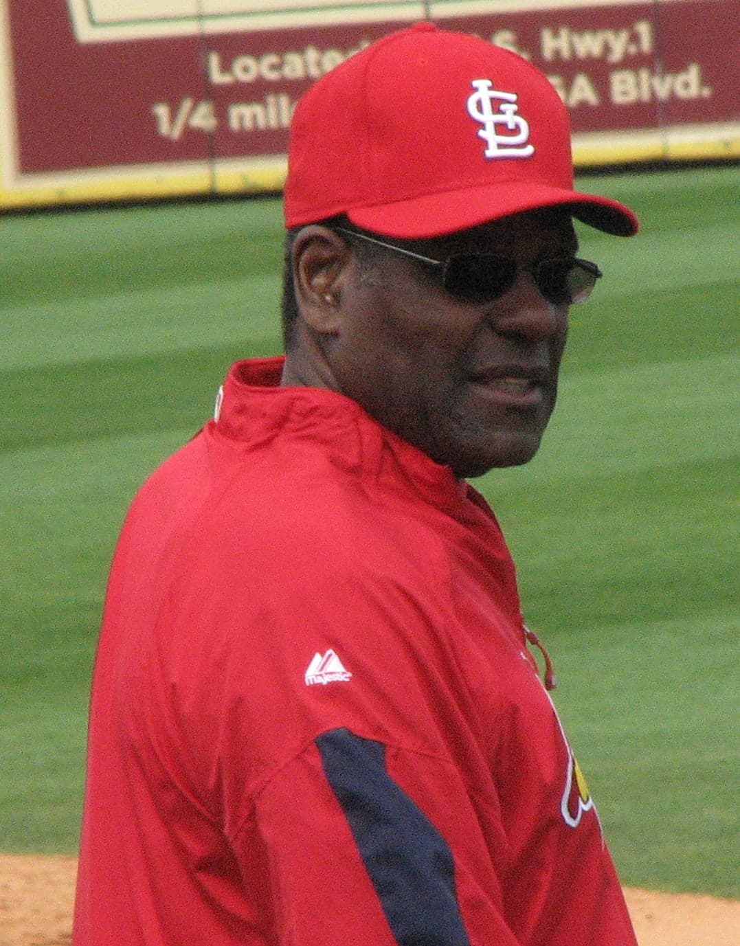Head-and-shoulders portrait of a man in a white baseball uniform with red piping and a red cap with the letters STL, looking directly at the camera with a serious expression.
