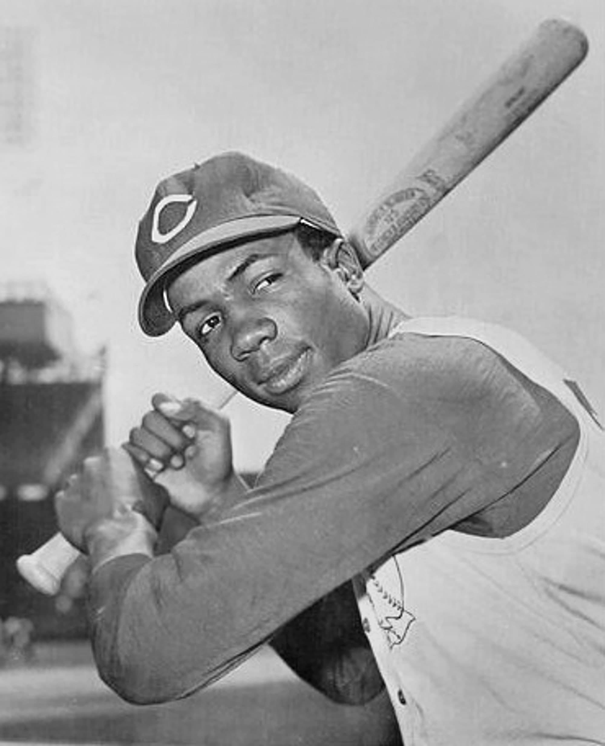 Head-and-shoulders portrait of a man in a white baseball uniform with red trim, a white cap with a red letter C on it, holding a bat across his chest, looking directly at the camera with a neutral expression.
