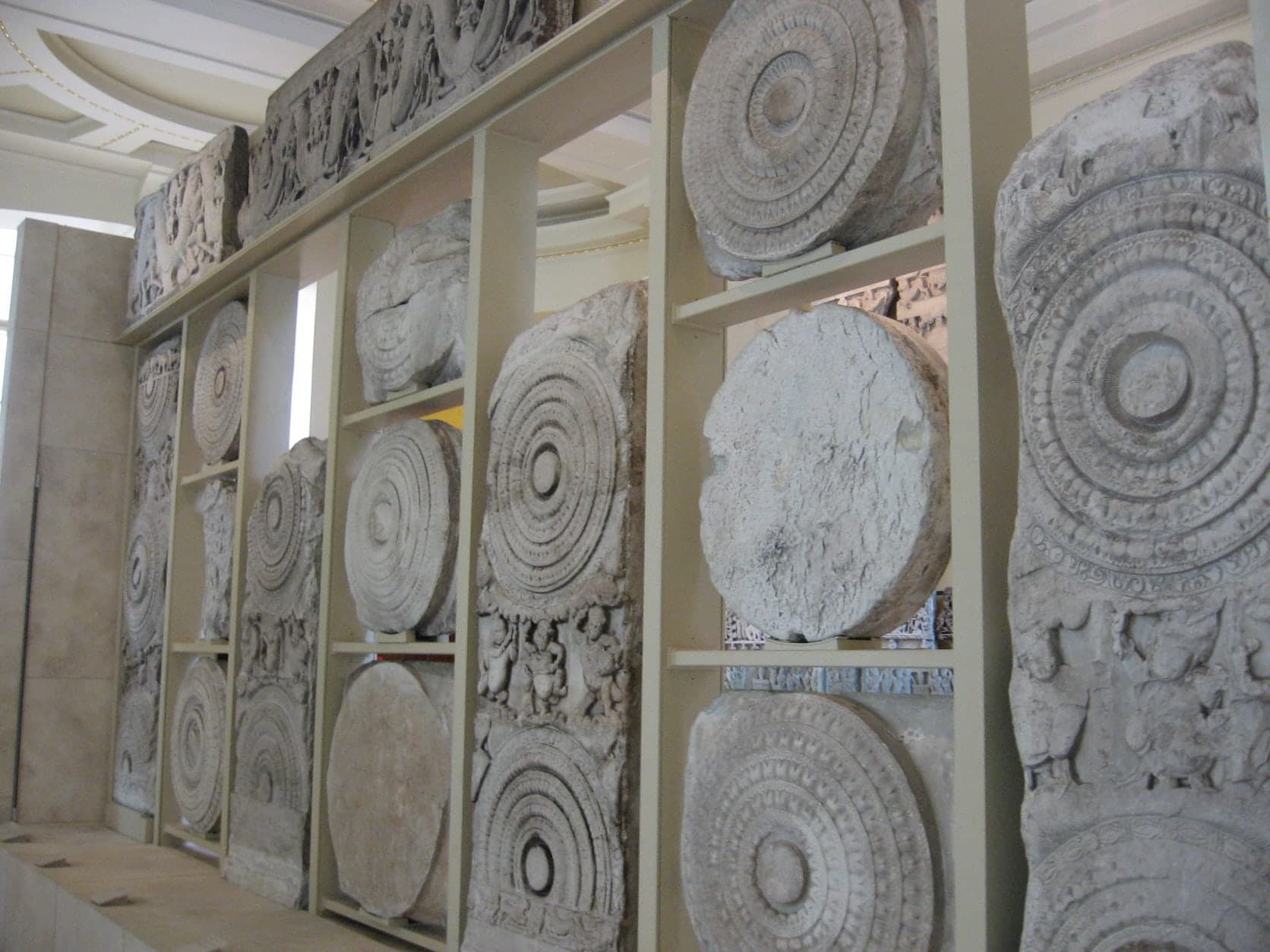 A series of carved limestone panels showing densely packed figures in narrative scenes, some crisp and detailed, others worn smooth by time.