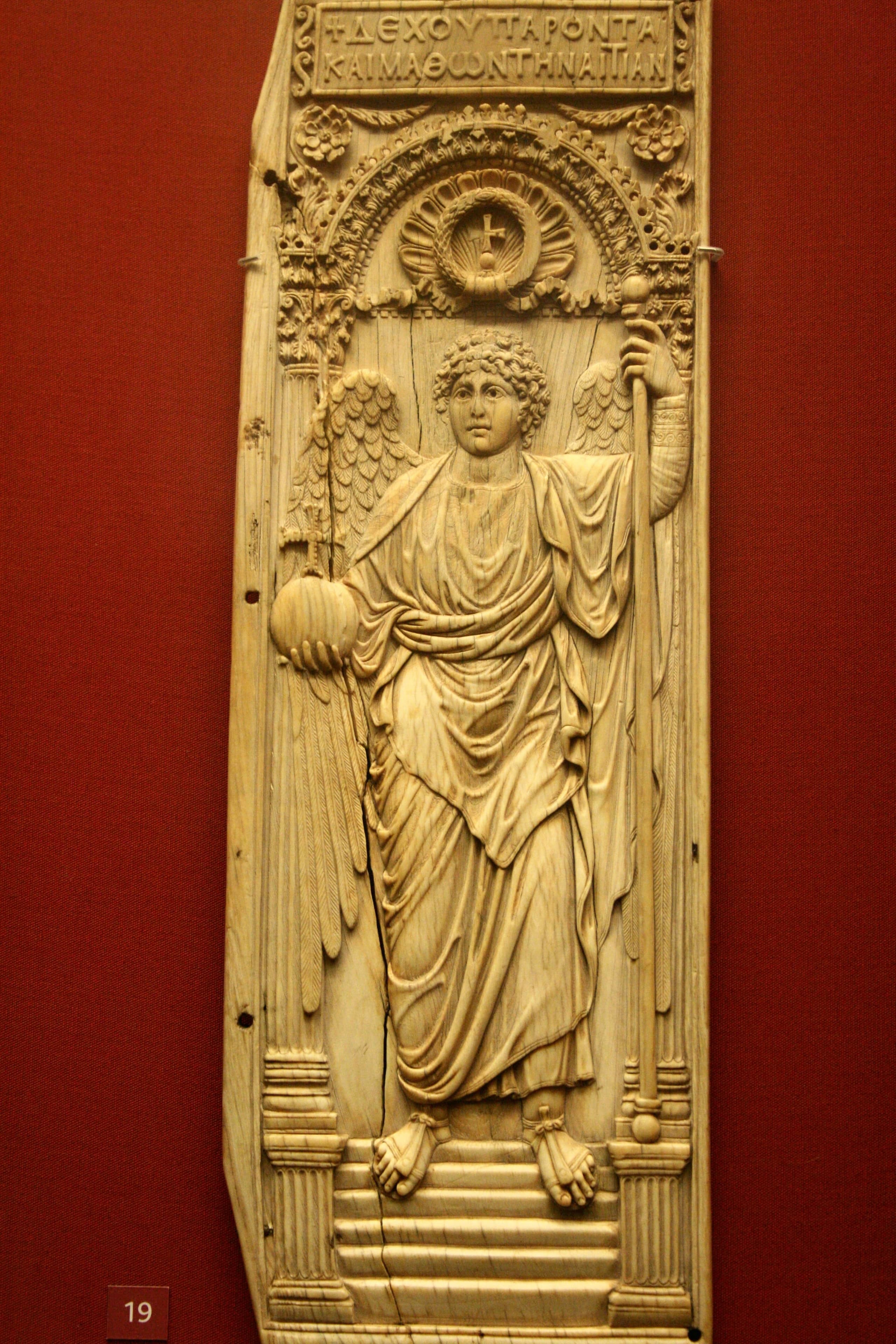 An ivory panel carved with a standing archangel who holds a sceptre and an imperial orb.