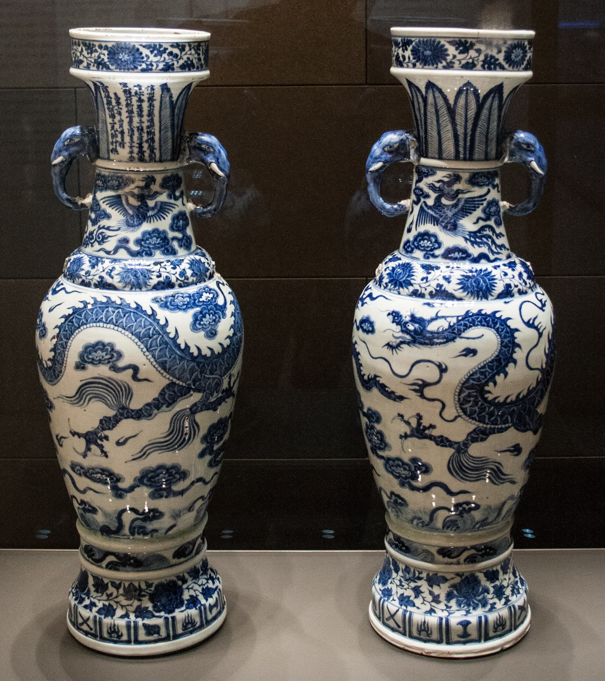 A pair of tall porcelain vases with elephant-head handles, decorated in cobalt blue with dense scrolling patterns, dragons, and bands of ornament against a white ground.