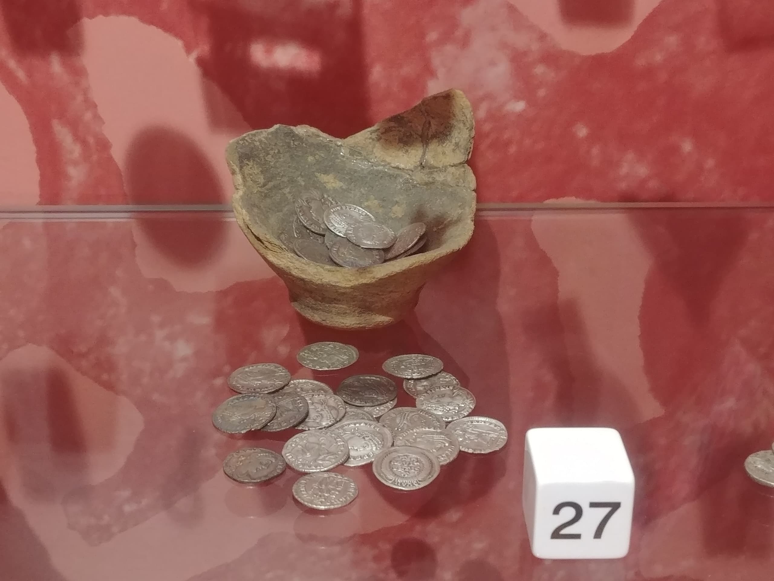 No image accompanies the supplied record, so visible details of the coins and ceramic cannot be described.