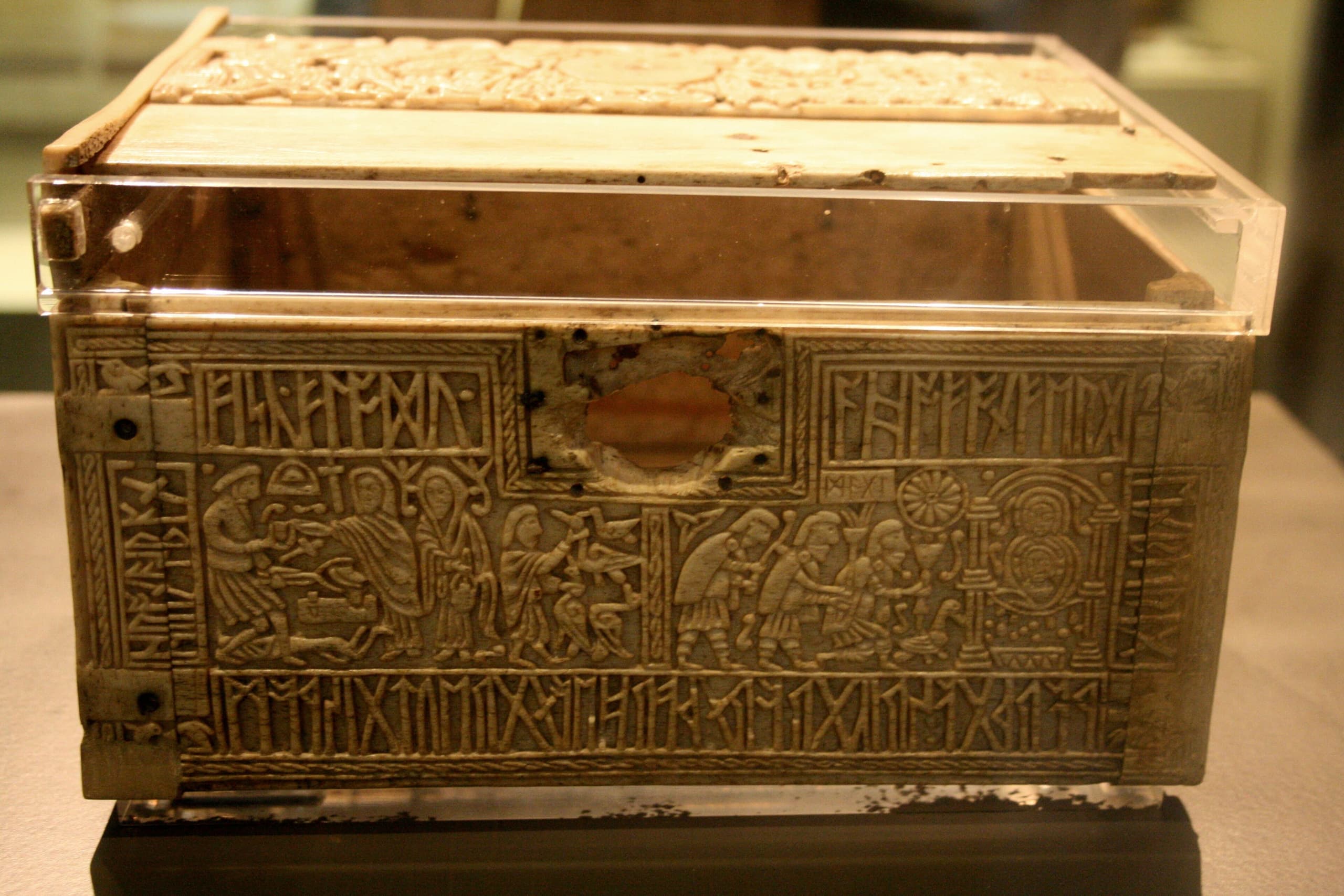 A small rectangular whalebone box densely carved in low relief with narrative scenes and runic inscriptions covering all visible surfaces.