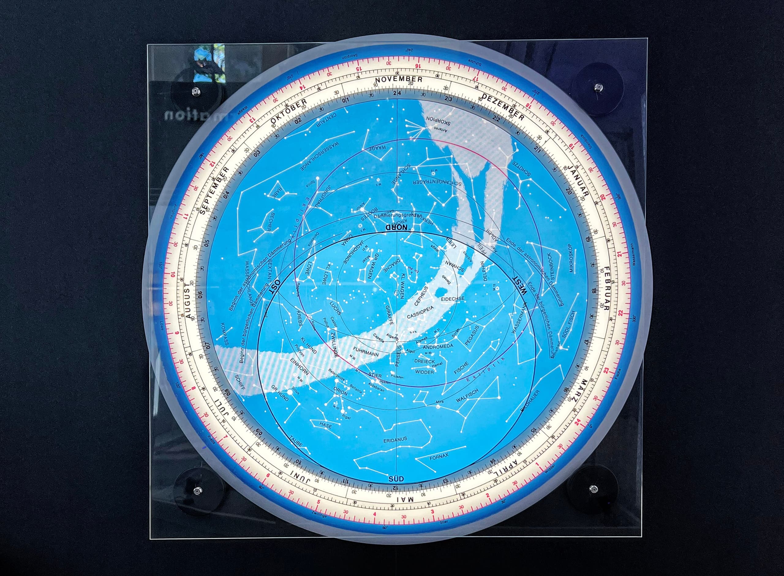 A circular brass disc with intricate engravings, featuring a pierced openwork overlay shaped like a web of curves and star pointers, rotatable over a base plate marked with degree scales and hour lines.