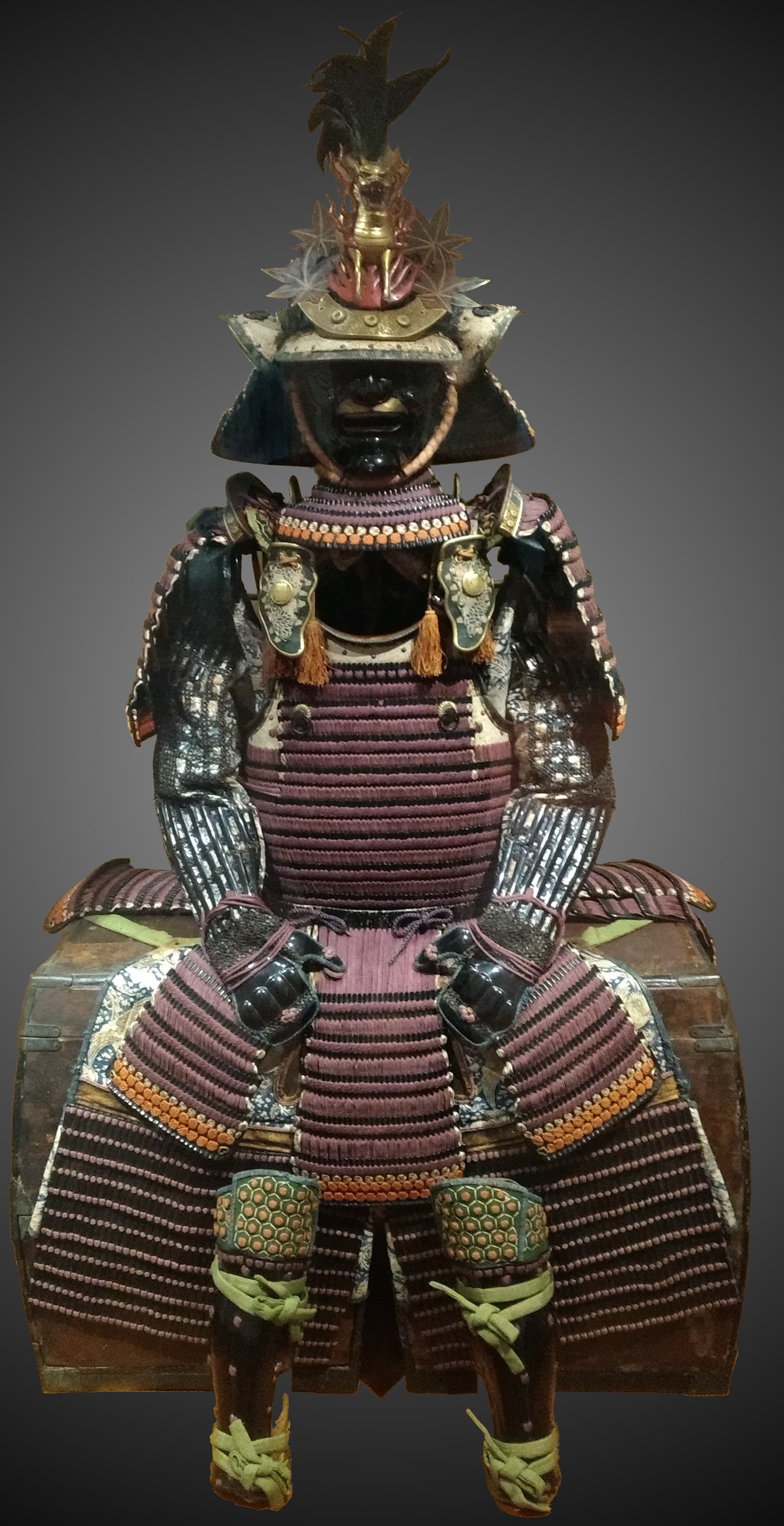 Samurai armour with lacquered iron scales laced together with coloured silk cord, showing a cuirass, shoulder guards, and helmet with face protection.