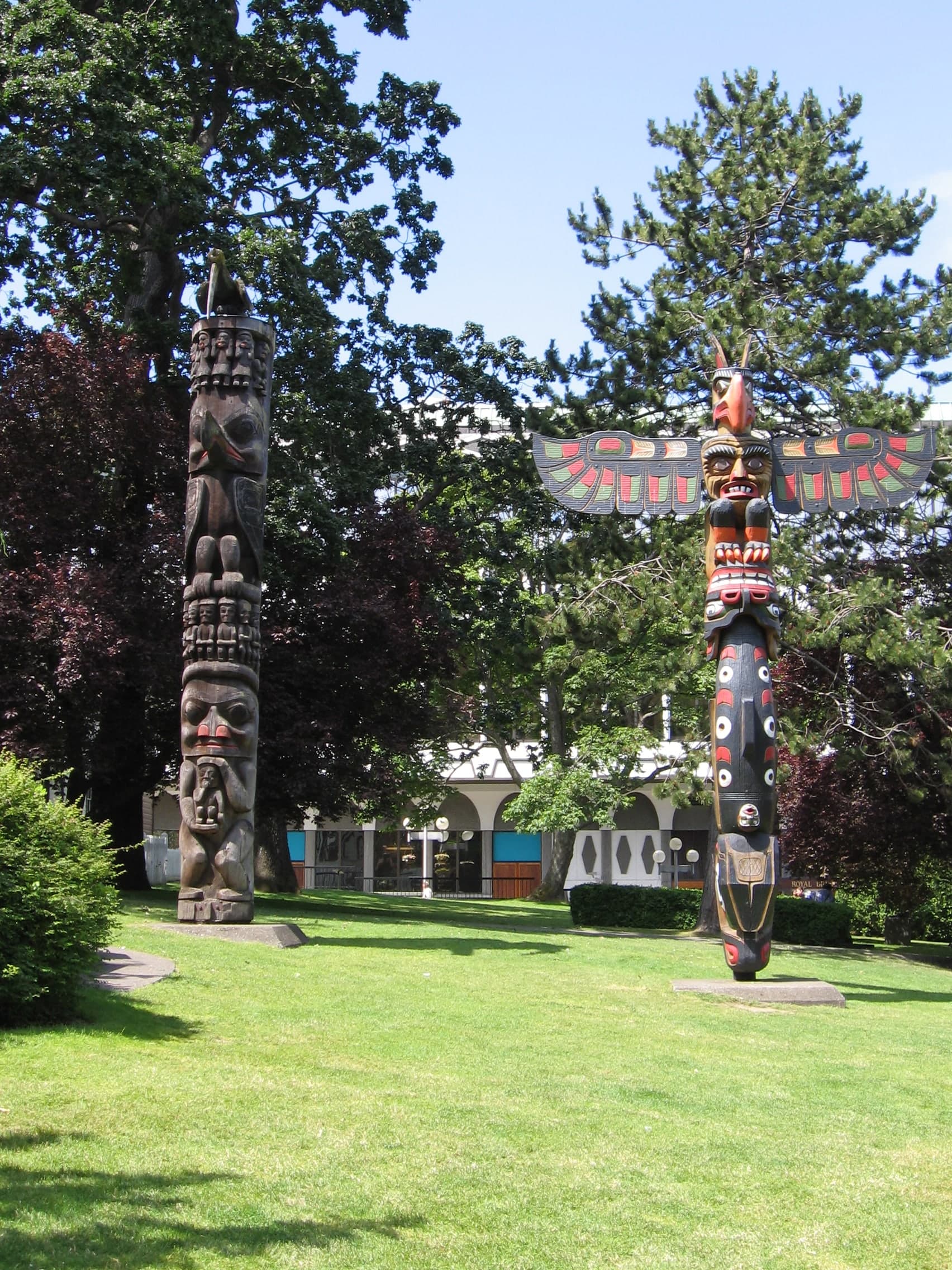 A tall carved wooden pole of western redcedar, with stacked figures including stylised animals and faces, each defined by bold cuts and curves that follow the wood's vertical grain.