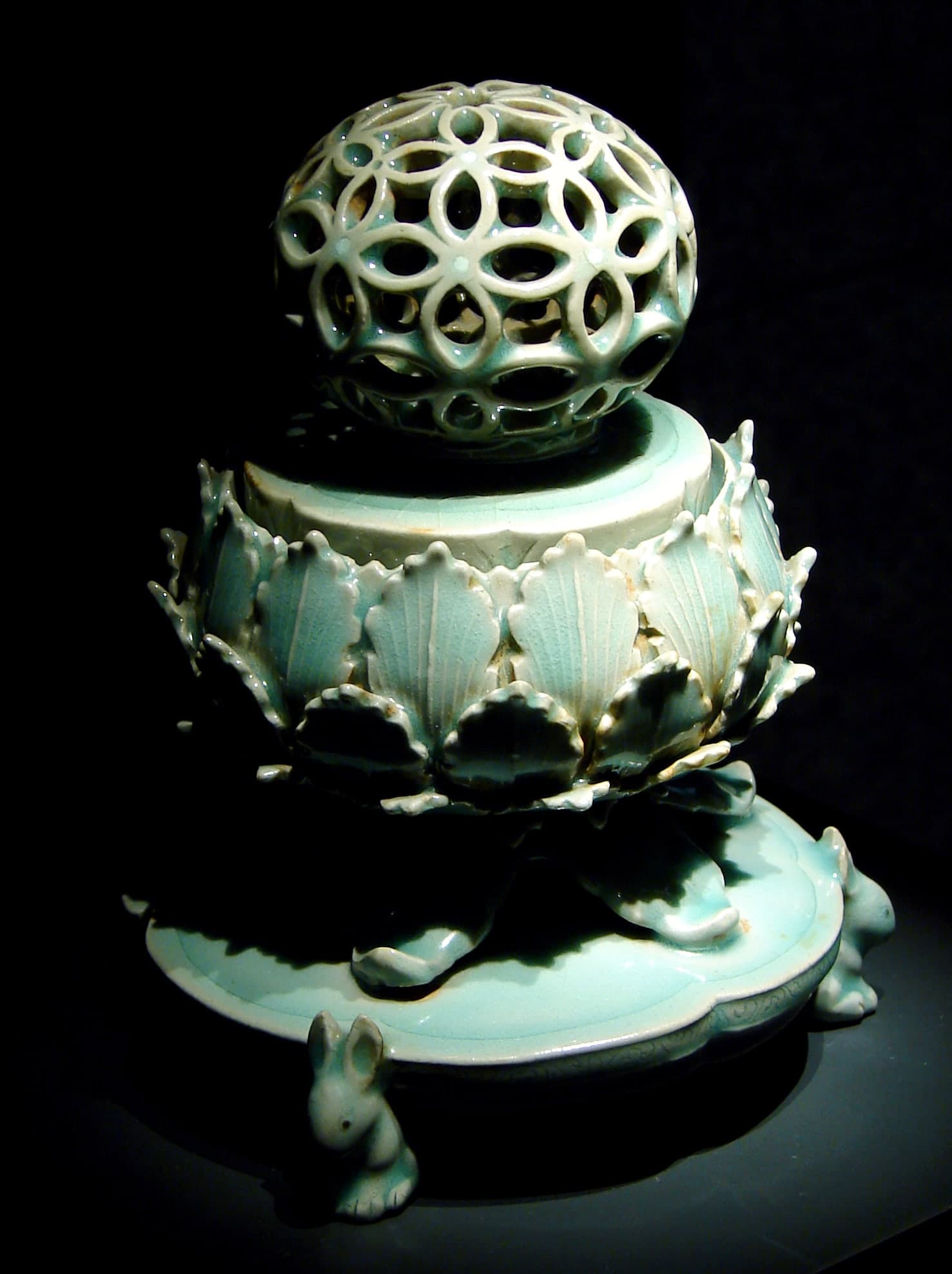 A pale blue-green glazed stoneware vessel with incised decoration filled with contrasting slip, visible beneath a translucent glaze.