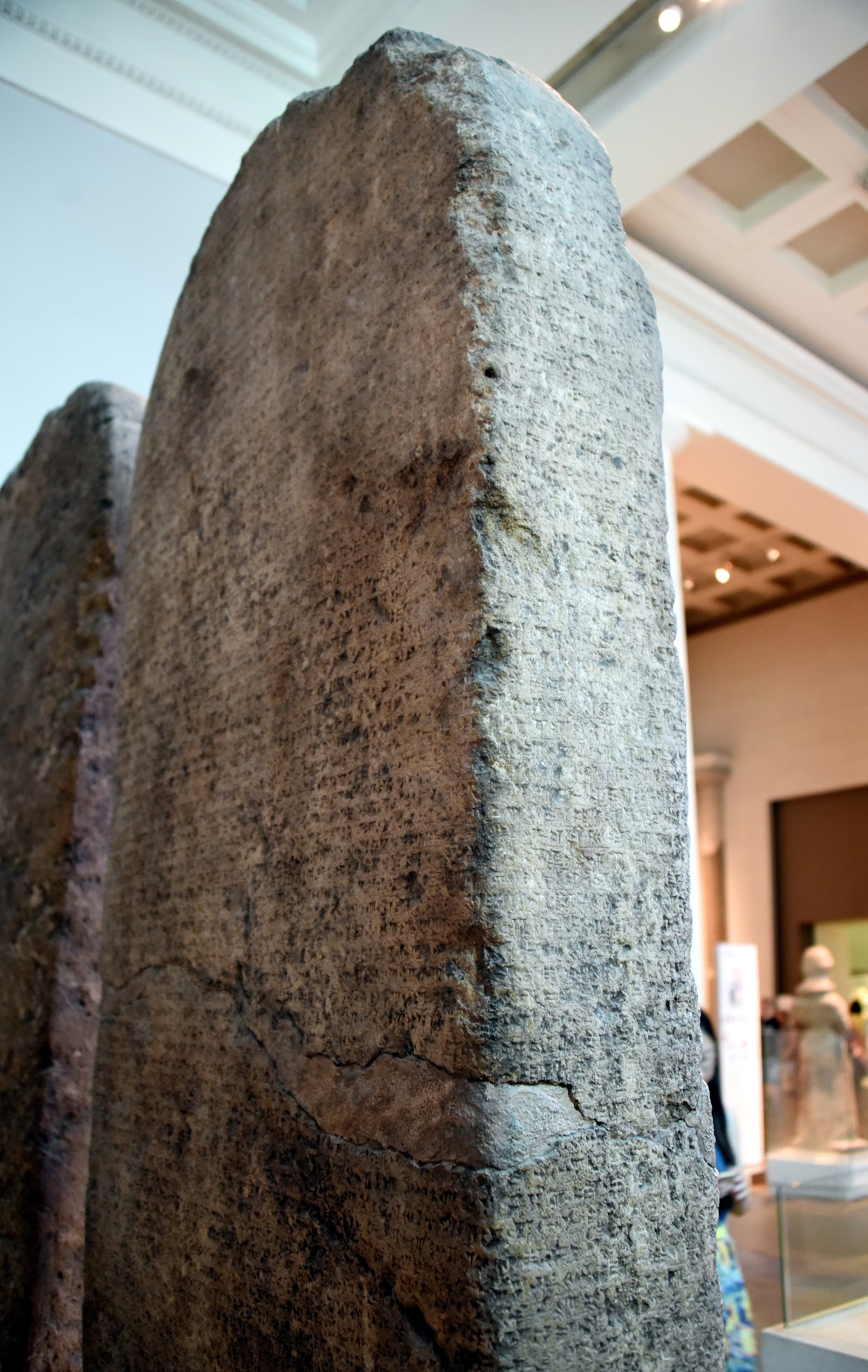 A tall limestone stela carved with dense cuneiform script, arranged in horizontal registers across the surface.