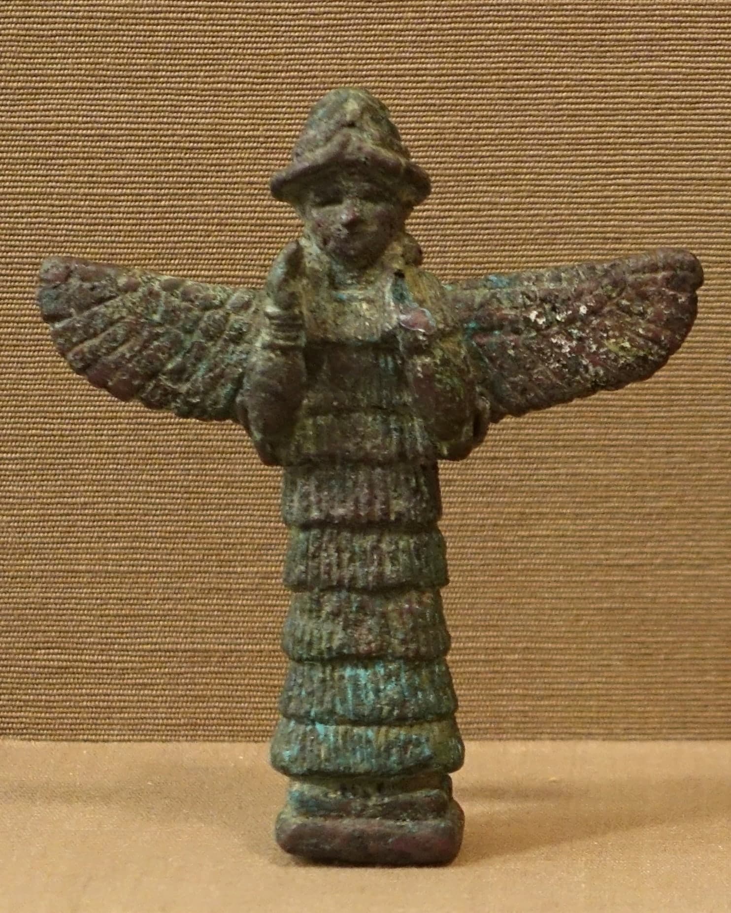 A massive stone relief of a winged bull with a bearded human head wearing a horned headdress, carved with five legs so that it appears complete from both the front and the side.