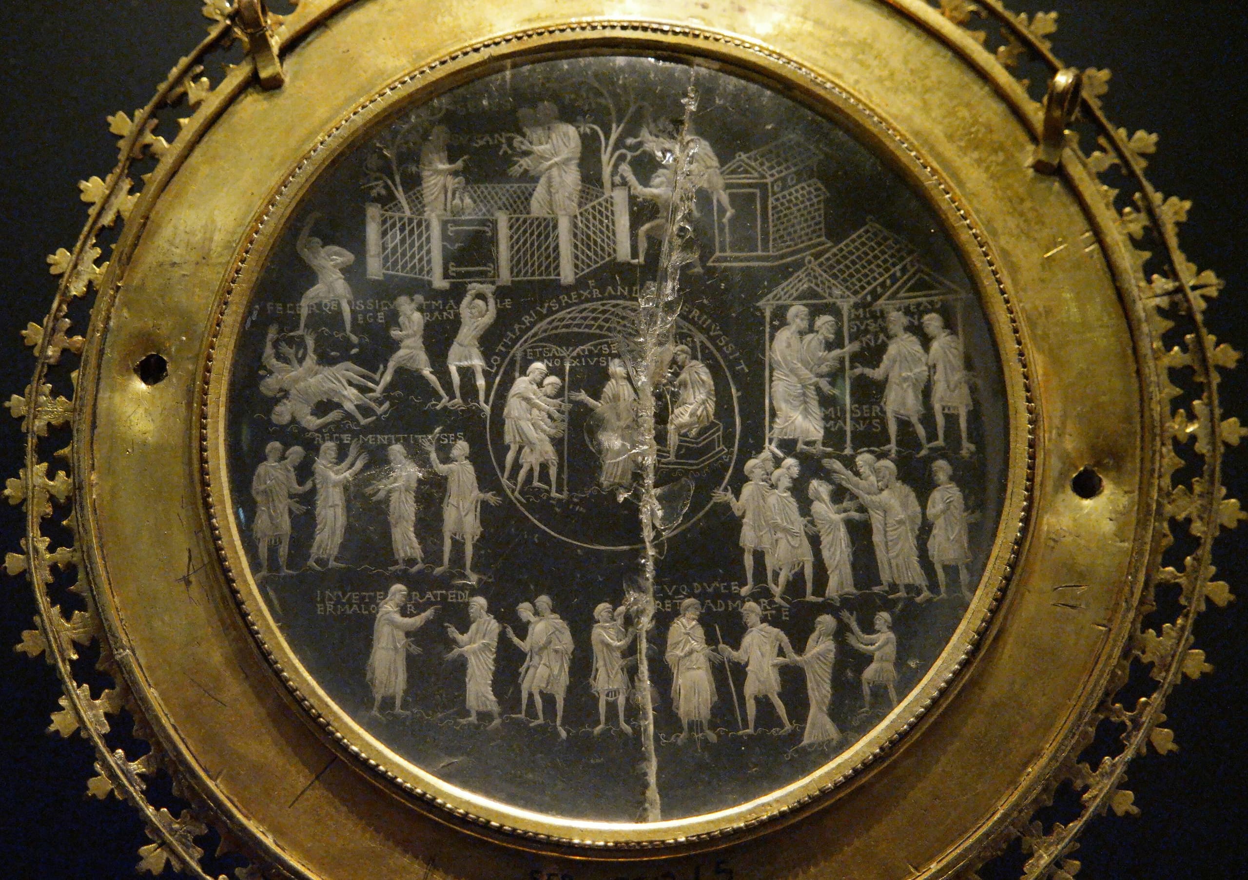 A circular disc of pale quartz, thinly cut and densely engraved with small figured scenes and inscriptions arranged across the face, shown against a neutral ground.