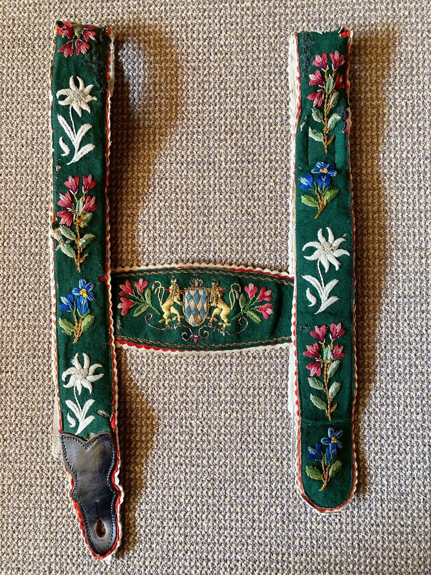 A section of tanned hide decorated with dyed porcupine quills stitched in geometric bands of red, yellow, black, and white, forming triangles and parallel lines.