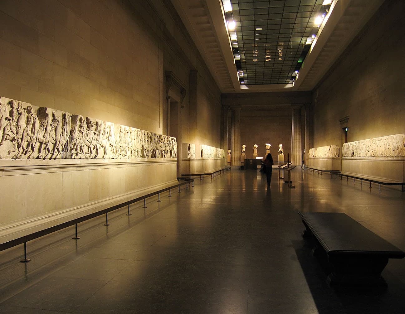 Pentelic marble relief sculptures and free-standing figures: a horseman in a flowing cloak, a seated figure in clinging drapery, a rearing horse with detailed musculature, and draped figures from a pediment group.