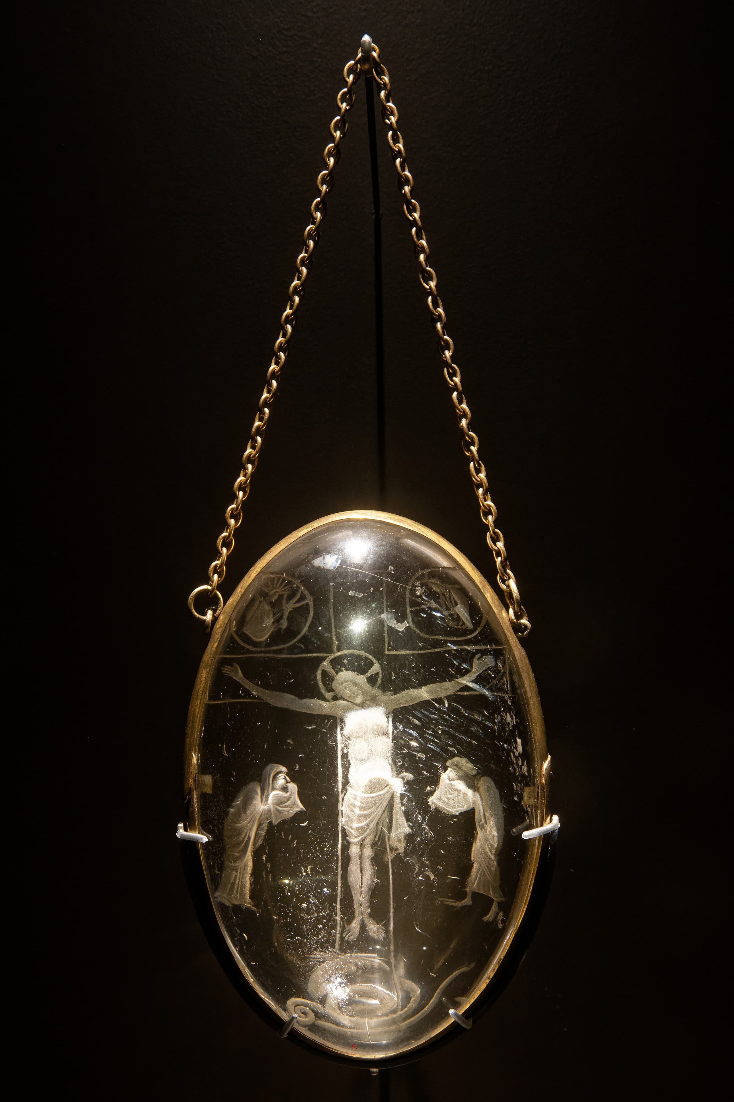 A thick block of colourless, transparent quartz engraved with the Crucifixion, the figure of Christ on the cross cut inwards into the stone in fine sunken lines that catch the light against the clear body of the crystal.