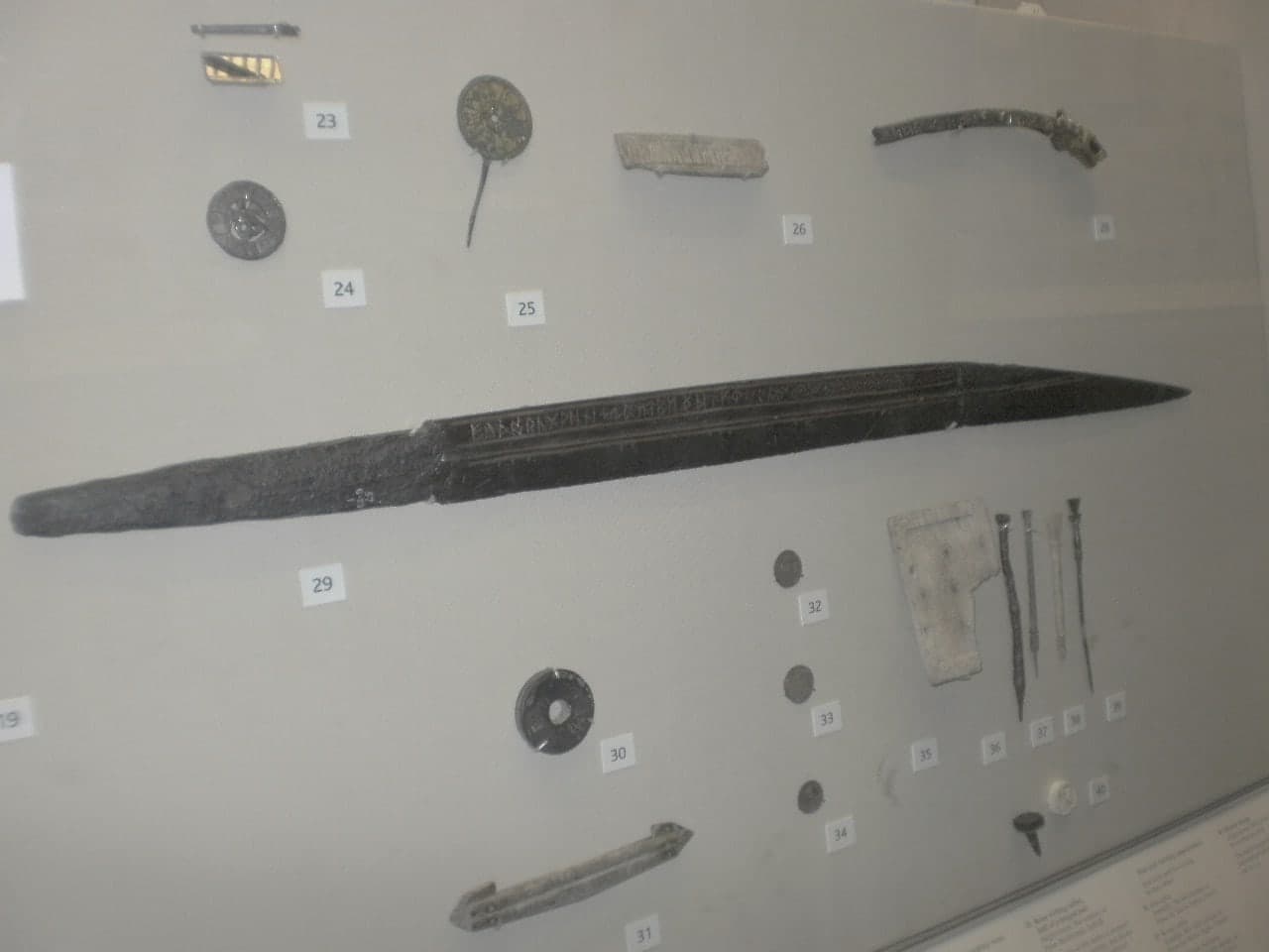 A long iron single-edged knife blade, decorated with fine contrasting metal inlay and a line of runic characters along one side.