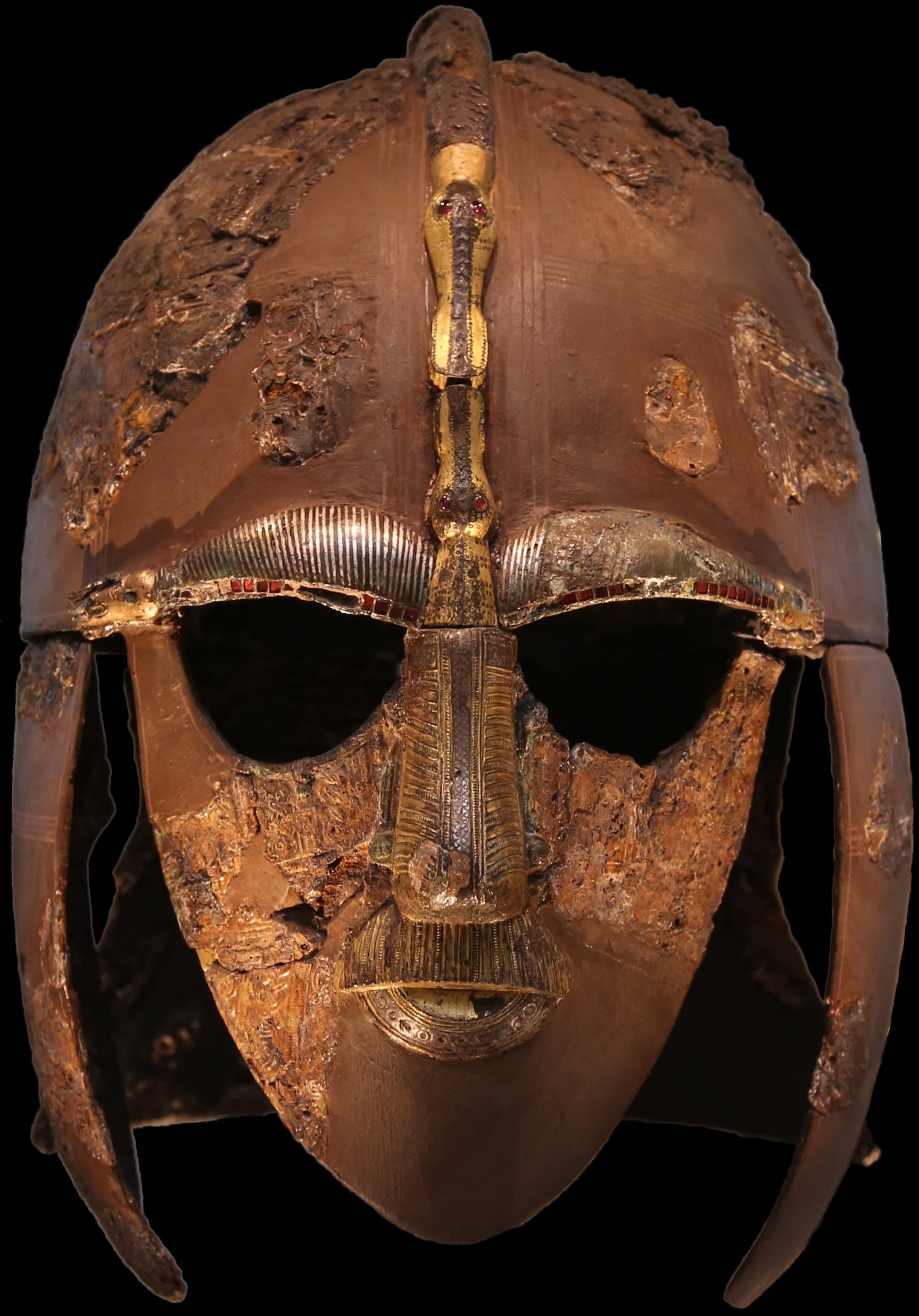 A reconstructed iron helmet with a face mask, eyebrows, nose and moustache formed from bronze and gold inlay in interlocking dragon and bird designs, displayed against a dark background.