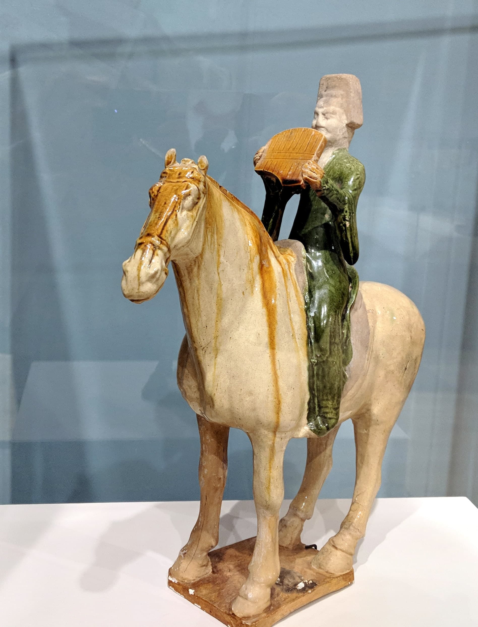 Glazed earthenware figures of a camel, horses, and grooms with Central Asian features, covered in streaked amber, green, and cream glazes.
